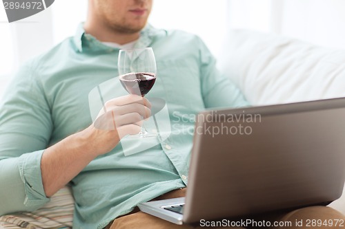 Image of close up of man with laptop and wine glass