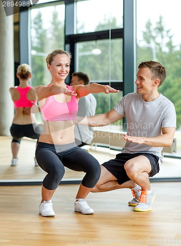 Image of smiling woman with male trainer exercising in gym