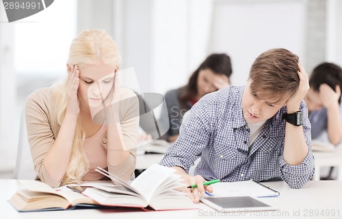 Image of tired students with tablet pc, notebooks and books