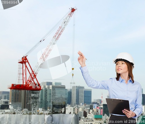 Image of smiling businesswoman in helmet with clipboard