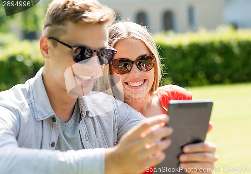 Image of smiling friends with tablet pc computers in park