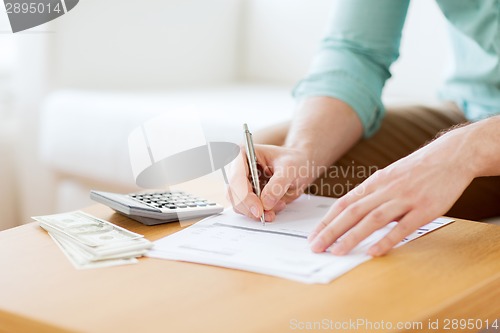 Image of close up of man counting money and making notes