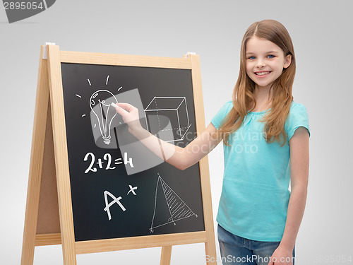 Image of happy little girl with blackboard and chalk