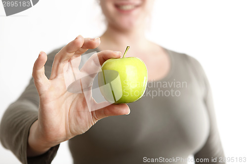 Image of Woman holds a green apple into to camera