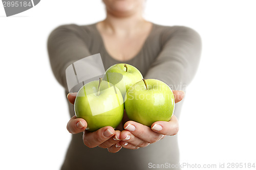 Image of Woman holds three green apples into to camera