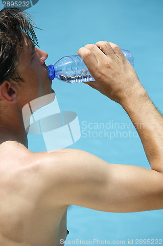 Image of Attractive man drinks water at the swimming pool