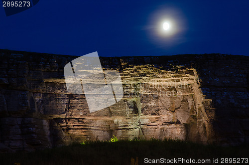 Image of Moon over illuminated limestone cliff