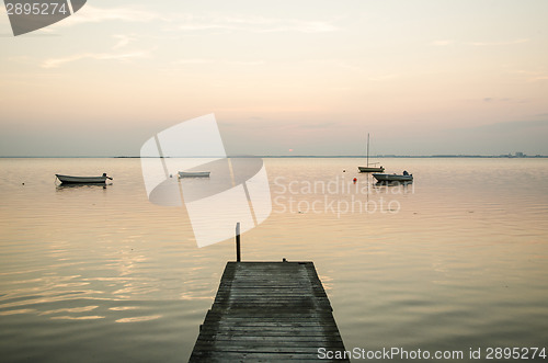 Image of Old jetty with anchored rowing boats in the water