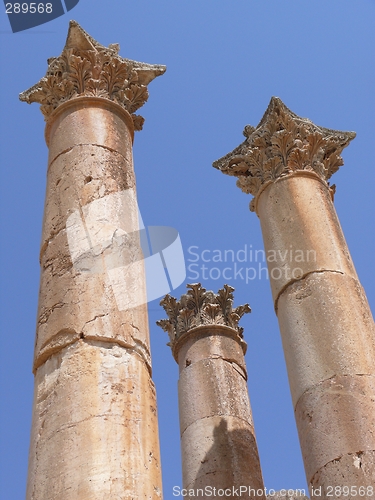 Image of Three ancient columns against clear blue sky, Jerash, Jordan