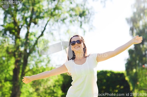 Image of smiling young woman with sunglasses in park