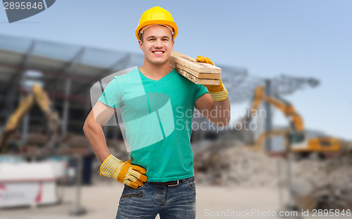 Image of smiling manual worker in helmet with wooden boards