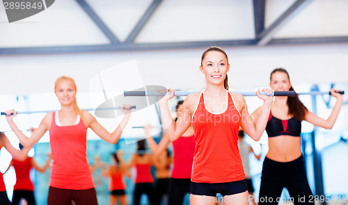 Image of group of smiling people working out with barbells
