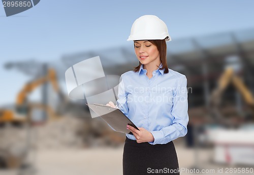 Image of smiling businesswoman in helmet with clipboard