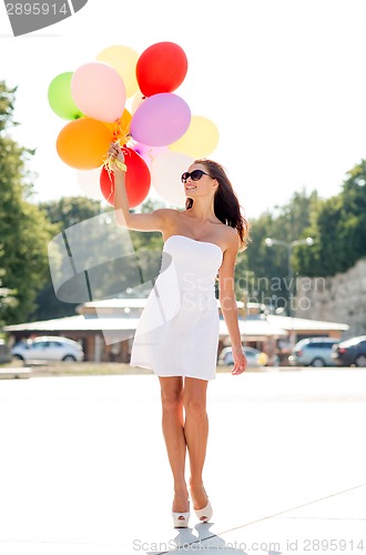 Image of smiling young woman in sunglasses with balloons