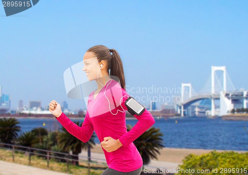 Image of smiling young woman running outdoors