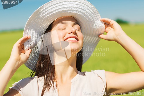 Image of smiling young woman in straw hat outdoors