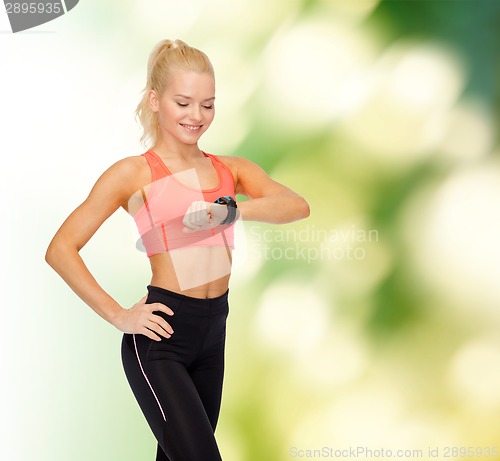 Image of smiling woman with heart rate monitor on hand