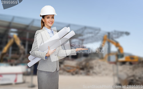 Image of smiling architect in helmet with blueprint