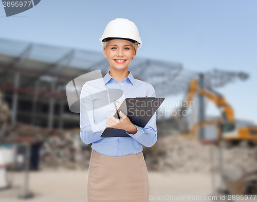 Image of smiling businesswoman in helmet with clipboard