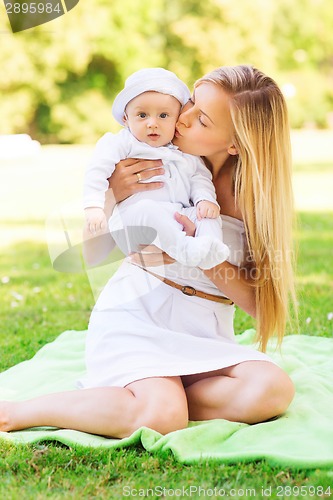 Image of happy mother with little baby sitting on blanket