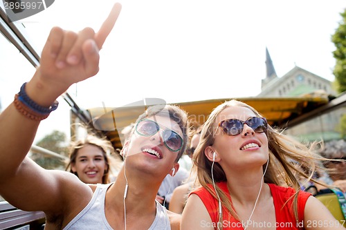 Image of smiling couple with earphones traveling by bus
