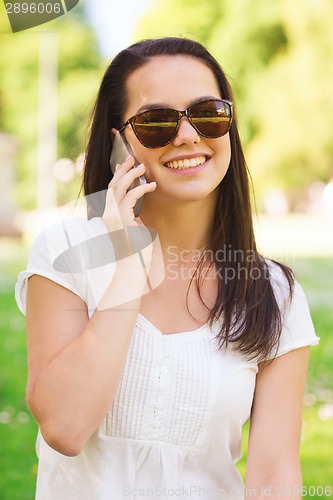 Image of smiling young girl with smartphone outdoors