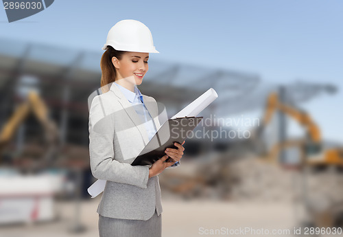 Image of smiling architect in helmet with blueprint