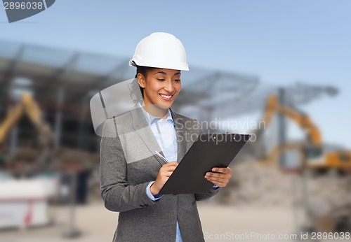 Image of smiling businesswoman in helmet with clipboard