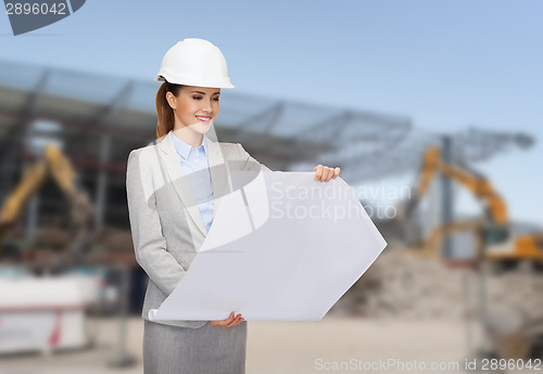 Image of businesswoman in white helmet with blueprint
