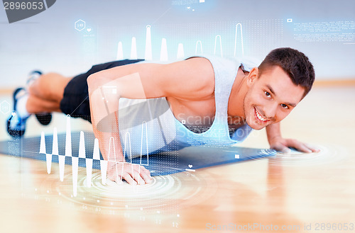 Image of smiling man doing push-ups in the gym