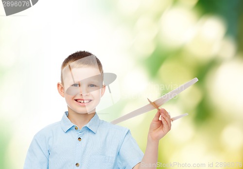 Image of smiling little boy holding a wooden airplane model