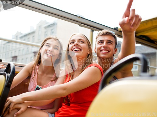 Image of group of smiling friends traveling by tour bus