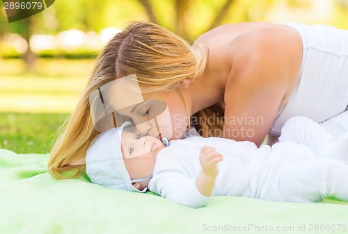 Image of happy mother lying with little baby on blanket