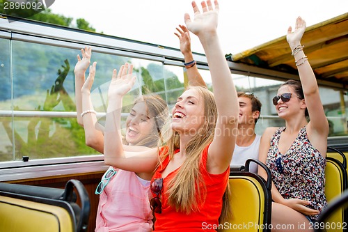 Image of group of smiling friends traveling by tour bus