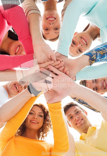 Image of smiling teenagers with hands on top of each other