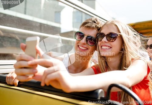 Image of smiling couple with smartphone making selfie