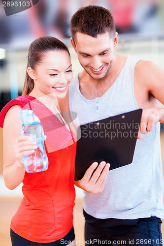 Image of smiling male trainer with woman in the gym