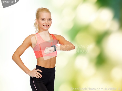 Image of smiling woman with heart rate monitor on hand