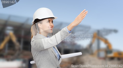 Image of smiling architect in helmet with blueprint