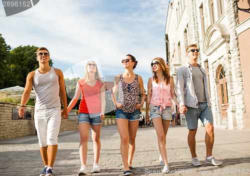 Image of group of smiling friends walking in city