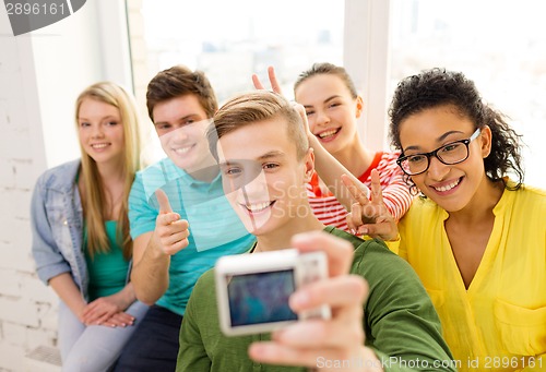 Image of five smiling students taking picture with camera