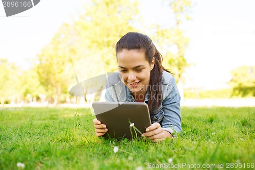 Image of smiling young girl tablet pc lying on grass