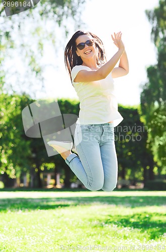 Image of smiling young woman with sunglasses in park