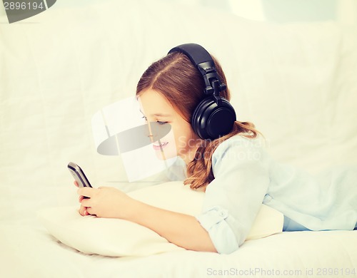 Image of girl with smartphone and headphones at home