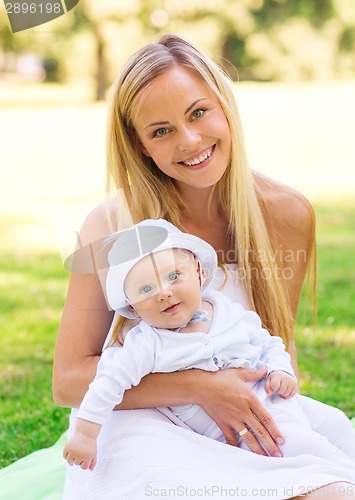 Image of happy mother with little baby sitting on blanket