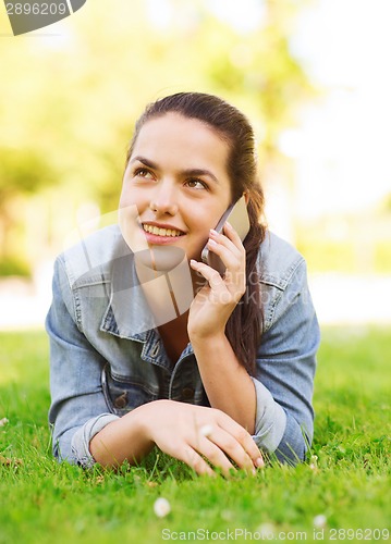 Image of smiling young girl with smartphone lying on grass