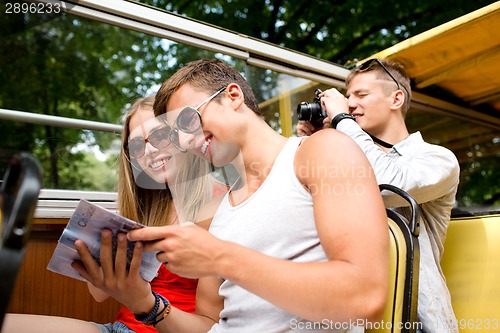 Image of smiling couple with book traveling by tour bus