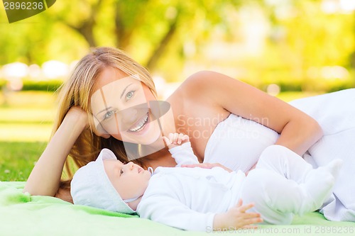 Image of laughing mother lying with little baby on blanket