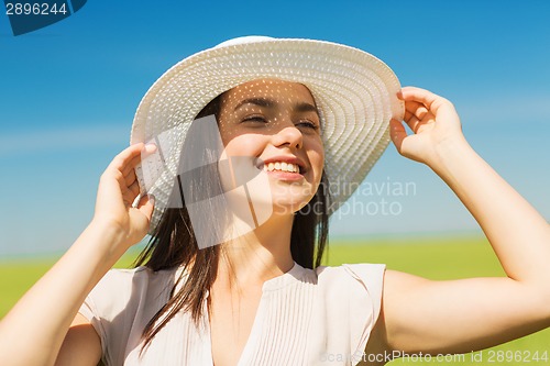 Image of smiling young woman in straw hat outdoors