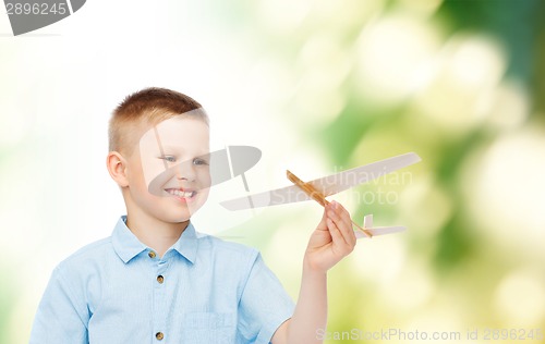 Image of smiling little boy holding a wooden airplane model